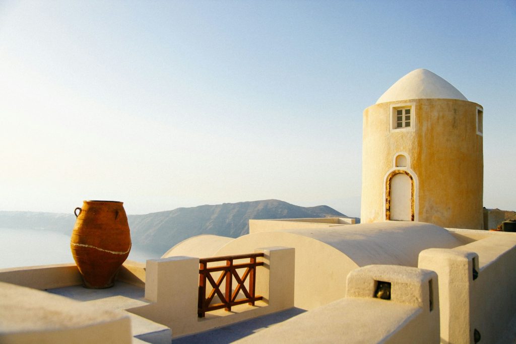 Traditional Mediterranean architecture featuring a whitewashed dome, terracotta pot, and stunning coastal views